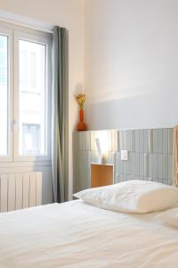 ein weißes Bett in einem Schlafzimmer mit einem Fenster in der Unterkunft T3 ** BALCON ** VIEUX PORT ** CENTRE in Marseille