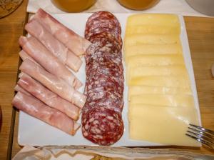 a plate with sausage and cheese on a table at B&B JONIO Roma in Rome