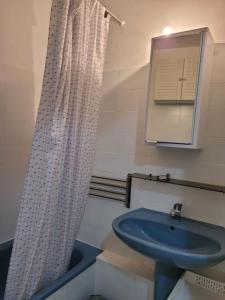 La salle de bains est pourvue d'un lavabo bleu et d'un rideau de douche. dans l'établissement Nice studio 30 m with terrace and pool, à Antibes