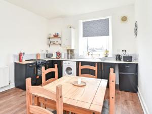 a kitchen with a wooden table and a dining room at John Muir Apartment in Helensburgh