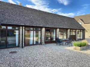 a house with a patio with a table and chairs at Stable Cottage, Old Mill Farm, Cotswold Water Park in Cirencester