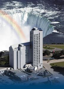 a rainbow over a building with a waterfall in the background at The Oakes Hotel Overlooking the Falls in Niagara Falls