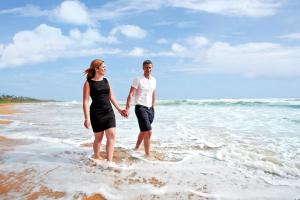a man and a woman standing in the water on the beach at Centara Ceysands Resort & Spa Sri Lanka in Bentota