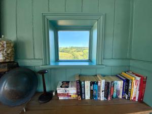 a shelf of books in a room with a window at Artist's Retreat - Old Signal Box - Private Sauna in Bath