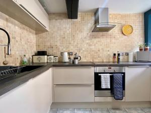 a kitchen with white cabinets and a stove at Historic Family Cottage - Central Frome in Frome
