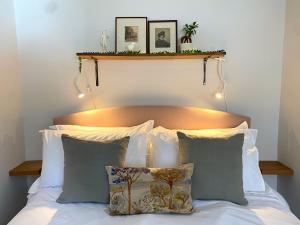 a bed with white sheets and pillows with lights above it at Historic Family Cottage - Central Frome in Frome