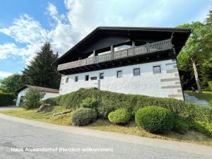 a white building with a balcony on the side of it at Große Ferienwohnung Hundertwasser am Dreisessel in Altreichenau in Neureichenau