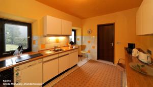 a kitchen with white cabinets and a sink and a window at Große Ferienwohnung Hundertwasser am Dreisessel in Altreichenau in Neureichenau