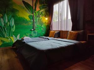 a bedroom with two beds with a tropical mural on the wall at โรงแรม บอร์ดดิ้งเฮ้าส์ in Ban Bang Yai Chuai