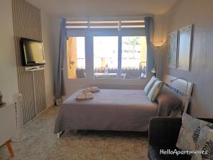 a bedroom with a bed with a window and a television at Arena Beach by HelloApartments in Puerto de Santiago