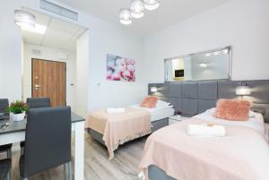 a room with two beds and a table and a desk at Warsaw Prymasa Tysiąclecia Business Centre by Renters in Warsaw