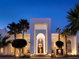 a white building with palm trees in front of it at Banyan Tree Tamouda Bay in Fnidek