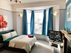 een slaapkamer met blauwe gordijnen, een bed en een televisie bij 4Alma St in Plymouth