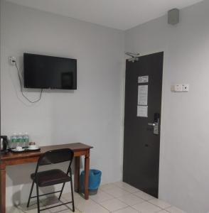 um quarto com uma secretária, uma porta preta e uma cadeira em Reintree Lodge Hotel em Ipoh