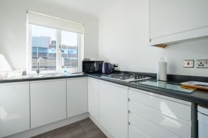a white kitchen with white cabinets and a window at The Douglas - Spacious 2 bed apartment in Uddingston in Uddingston