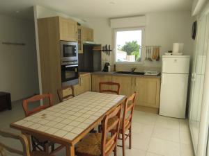 eine Küche mit einem Tisch und Stühlen sowie einem weißen Kühlschrank in der Unterkunft Maison neuve dans Saintes avec terrasse et jardin in Saintes