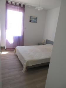 ein weißes Schlafzimmer mit einem Bett und einem Fenster in der Unterkunft Maison neuve dans Saintes avec terrasse et jardin in Saintes