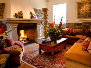 a living room with a fireplace with couches and a table at Inkaterra La Casona Relais & Chateaux in Cusco