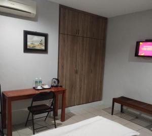 um quarto com uma secretária, uma cadeira e uma televisão em Reintree Lodge Hotel em Ipoh
