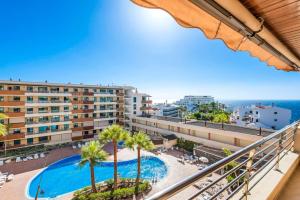 a balcony with a swimming pool and palm trees at Bright and welcoming holiday home in Puerto de Santiago