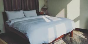 台南的住宿－民生綠園，一间卧室配有一张带白色床单的大床