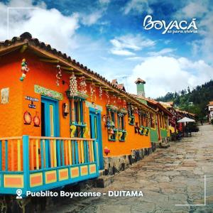 een oranje gebouw met blauwe ramen op een straat bij Casa Posada Maestro Carlos Aranguren in Duitama