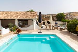 a blue swimming pool in front of a house at Cortijo mirasol in Santa Cruz de Comercio