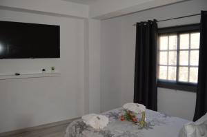 Habitación blanca con TV y mesa con flores. en Casa Rural Guadá, en Valle Gran Rey