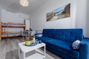 a living room with a blue couch and a table at Apartament AKWAMARYN z bezpłatnym parkingiem Dziwnówek nad morzem 250m od plaży Epapartamenty in Dziwnówek
