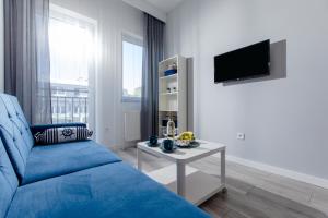 a living room with a blue couch and a tv at Apartament AKWAMARYN z bezpłatnym parkingiem Dziwnówek nad morzem 250m od plaży Epapartamenty in Dziwnówek