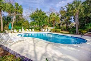 a swimming pool with chairs and palm trees at Turtle View Villa in Hilton Head Island