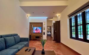 a living room with a blue couch and a tv at Adrak Mountain Mist Forest Resort in Pulpally