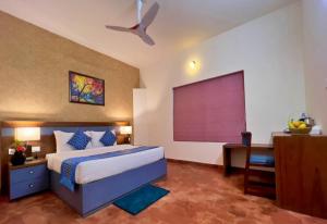 a bedroom with a bed and a desk and a window at Adrak Mountain Mist Forest Resort in Pulpally