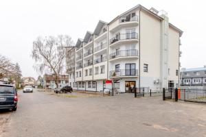 a large white building with cars parked in front of it at Apartament AKWAMARYN z bezpłatnym parkingiem Dziwnówek nad morzem 250m od plaży Epapartamenty in Dziwnówek