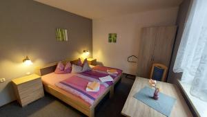 a small bedroom with a bed and a table at Pension & Gasthof "Am Park" UG in Stützerbach