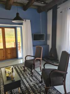 een woonkamer met 2 stoelen, een tafel en een tv bij Harmonie Farm Cottages in Montagu