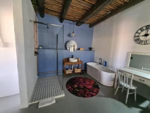 een badkamer met een bad en een klok aan de muur bij Harmonie Farm Cottages in Montagu