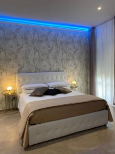 a bedroom with a large white bed with a blue light at b&b THE WORLD in Brindisi