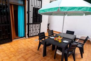 a black table and chairs with a green umbrella at Casa Sami in Playa de las Americas