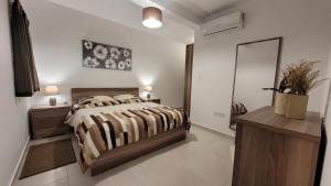a white bedroom with a bed and a mirror at Lovely Apartment with Side Sea View in St Paul's Bay