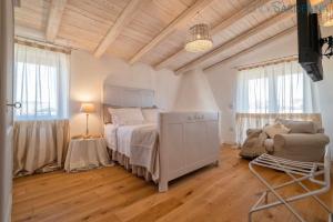 1 dormitorio con cama, sofá y ventanas en Tenute Shardana Luxury Farmhouse with SPA, Sauna, Heated Swimming Pool en Mores