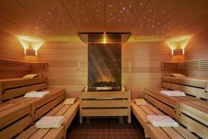a sauna with wooden walls and benches and a fireplace at Sunday Hotel Friedrichroda & SPA in Friedrichroda