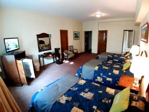 una camera d'albergo con due letti e una televisione di Hotel MAURY a Lima