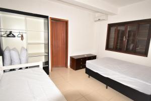 um quarto com uma cama e uma janela em Casa Canela, 450 mts da Praia de Mariscal. em Bombinhas