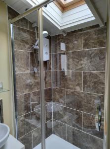 a shower with a glass door in a bathroom at Conygre Bungalow in Timsbury