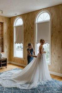Une femme aidant une mariée dans sa robe de mariée dans l'établissement Cornerstone Inn, à Washington