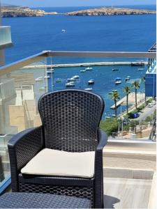 uma cadeira sentada numa varanda com vista para o oceano em Lovely Apartment with Side Sea View em St. Paul's Bay