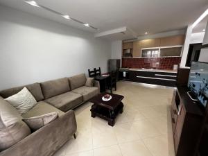 een woonkamer met een bank en een keuken bij Grande Veranda 2 in Tirana