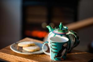 a table with a coffee cup and cookies and a teapot at An Cala Beag Self Catering apartment on The Waternish Peninsula in Hallin