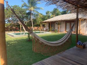 a hammock in front of a house with a pool at Casa Rosa Atins in Atins